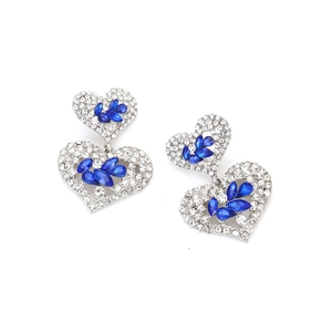 Détail de boucles d'oreilles pendantes en forme de cœur avec strass argentés et cristaux bleus