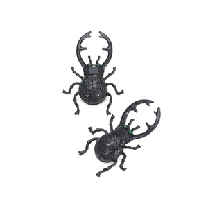 Auffällige schwarze Käfer-Ohrringe mit grünen Steinaugen und Labyrinth-Struktur