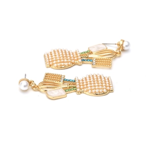 Detail of gold earrings shaped like baskets with white pearls and colorful rhinestones