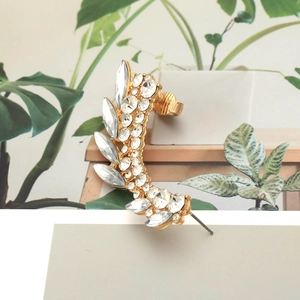 Exaggerated golden leaf ear cuff with colorful crystals and pearls in a nature-themed shot