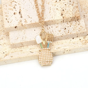 Détail du pendentif créatif en ustensiles de cuisine dorés avec perles et émail