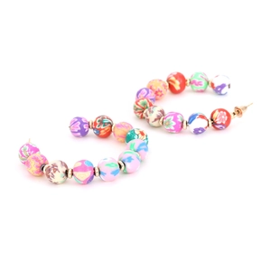Detail of bohemian C-shaped earrings with colorful floral clay beads and gold accents
