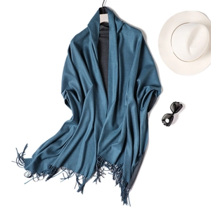 Detail of navy cashmere-feel scarf with fringes styled with elegant hat and sunglasses
