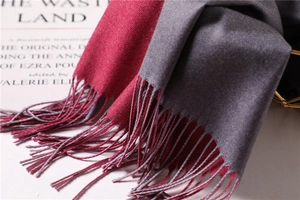 Macro shot of bicolor cashmere-feel scarf with elegant tassels and dark red-grey fabric texture