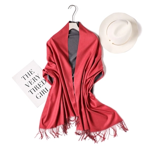 Detail of red and grey double-sided cashmere-like scarf with fringe on wooden hanger