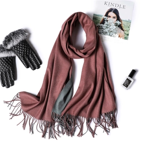 Detail of warm brick red scarf with tassels and black quilted gloves for winter