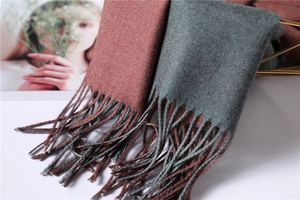 Detail view of thick double-sided cashmere scarf with long fringe in brick red and green