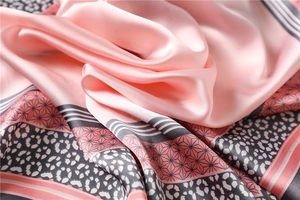 Détail d'un foulard en soie rose avec imprimé léopard et motifs géométriques en gros plan