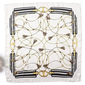 Detail view of square silk scarf featuring golden chain patterns and striped borders