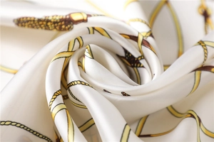 Detailed macro shot of elegant silk square scarf with golden chain and tassel prints