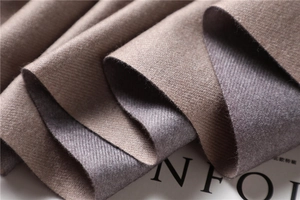 Detail of double-sided cashmere-like scarf showing twill texture in brown and purple grey