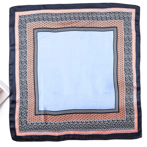 Vue à plat d'un foulard en soie bleu clair avec des bordures à motifs floraux