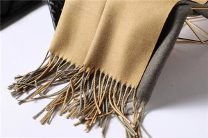 Close-up of double-sided cashmere scarf in camel and dark grey with fringe tassels