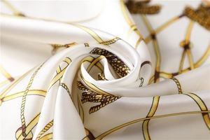 Macro shot of elegant white silk scarf with gold rope and chain pattern detailing
