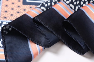 Détail macro du foulard en satin aux motifs géométriques et texture soyeuse raffinée