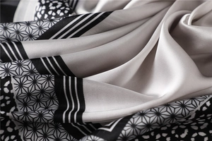 Vue détaillée d'un foulard en soie gris et noir avec motifs d'étoiles géométriques et rayures