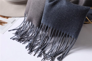 Close-up of double-sided cashmere-like scarf with fringe detail in gray and navy blue