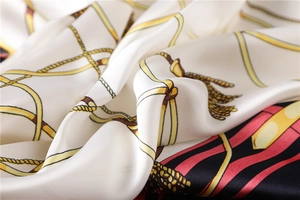 Close-up of silky fashion square scarf featuring elegant gold chain and tassel patterns