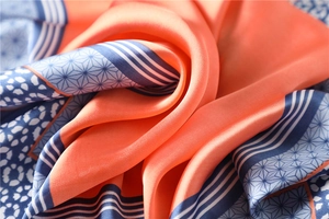Vue macro d'un foulard en soie orange et bleu avec motifs géométriques et texture lisse