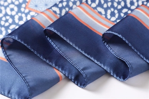 Détail d'un foulard en soie bleue avec motifs léopard et géométriques à bordure orange