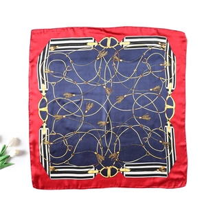 Flat lay of red and blue silk scarf with golden chain patterns and white tulip