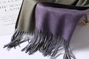 Close-up of double-sided cashmere-like scarf with long fringe in purple and dark green