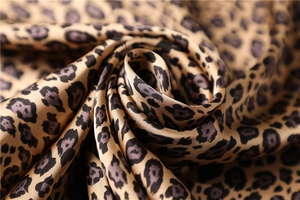 Close-up of leopard print satin fabric with metallic luster and elegant spiral drapes