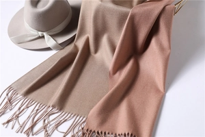 Detail of soft cashmere-feel scarves in camel and blush pink with tassel edges