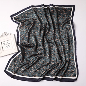 Close-up of leopard print silk scarf in navy and orange with smooth satin texture