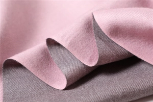 Detailed close-up of double-sided cashmere scarf in pink and mauve with twill texture