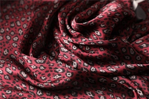 Close-up of leopard print satin scarf showing smooth silk texture and red black pattern
