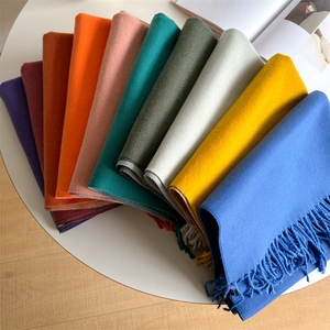 Macro detail of colorful winter scarves with long fringes displayed in a fan arrangement