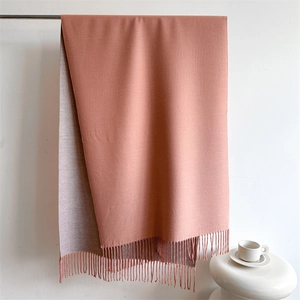 Detail view of a thick double-sided pink cashmere-like scarf with elegant tassels