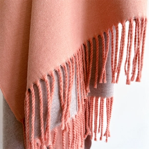 Detailed macro view of soft dual-color knit shawl with delicate fringed edge details