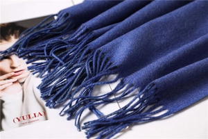 Detailed close-up of navy blue cashmere scarf texture with delicate fringed edges