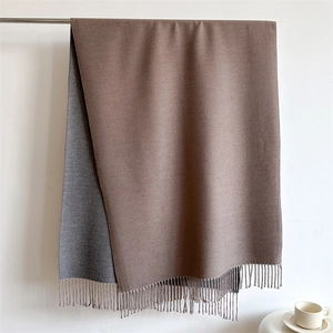 Detail of soft double-sided scarf showing grey and brown tones with fringe trim