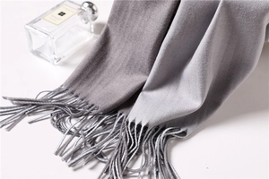Detail of grey cashmere-like scarf showing fine twill texture and soft fringe tassels