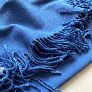 Detailed close-up of blue knit cashmere scarf featuring handcrafted fringe edges