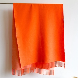 Detail of bright orange winter scarf showing thick knit texture and fringe tassels