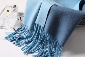 Detail of two-tone blue cashmere scarf with fine knit texture and fringe edge
