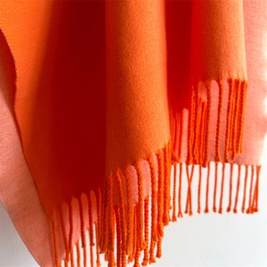 Macro detail of bright orange cashmere feel scarf with high density fringe tassels
