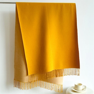 Detailed texture of ginger and camel cashmere-feel scarf with elegant fringe tassels