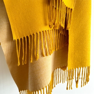 Close-up of thick yellow cashmere feel scarf showing soft woven texture and tassel fringes