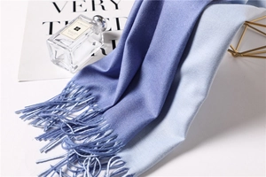 Detailed view of ombre blue cashmere scarf featuring long fringe and twill texture