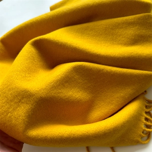 Detail shot of soft mustard yellow cashmere-like scarf showing warm fringe and fine texture