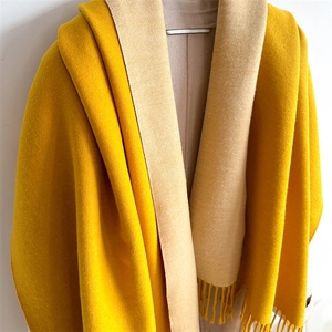Detail of dual-color yellow and beige scarf with tassel trim and soft cashmere texture