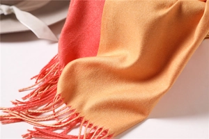 Detail of soft cashmere-like scarf with orange and pink dual-tone finish and tassels