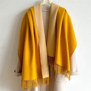 Detail view of double-sided cashmere-feel scarf in yellow and beige with long tassels