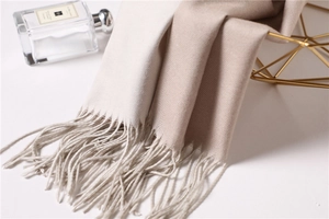 Close-up of beige pashmina shawl with long fringe tassels and soft knit texture