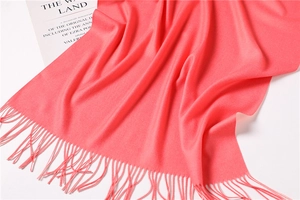 Detail of coral pink double-sided cashmere scarf with soft fringes and fine texture